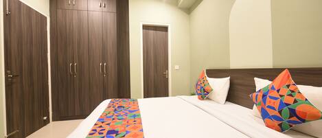 A bedroom with a large bed, two wardrobes, and a colorful bed runner.