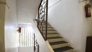 A staircase with black steps and a metal railing, leading to a landing with a white door. - Fabhotel Comfort Stays (Panaji)