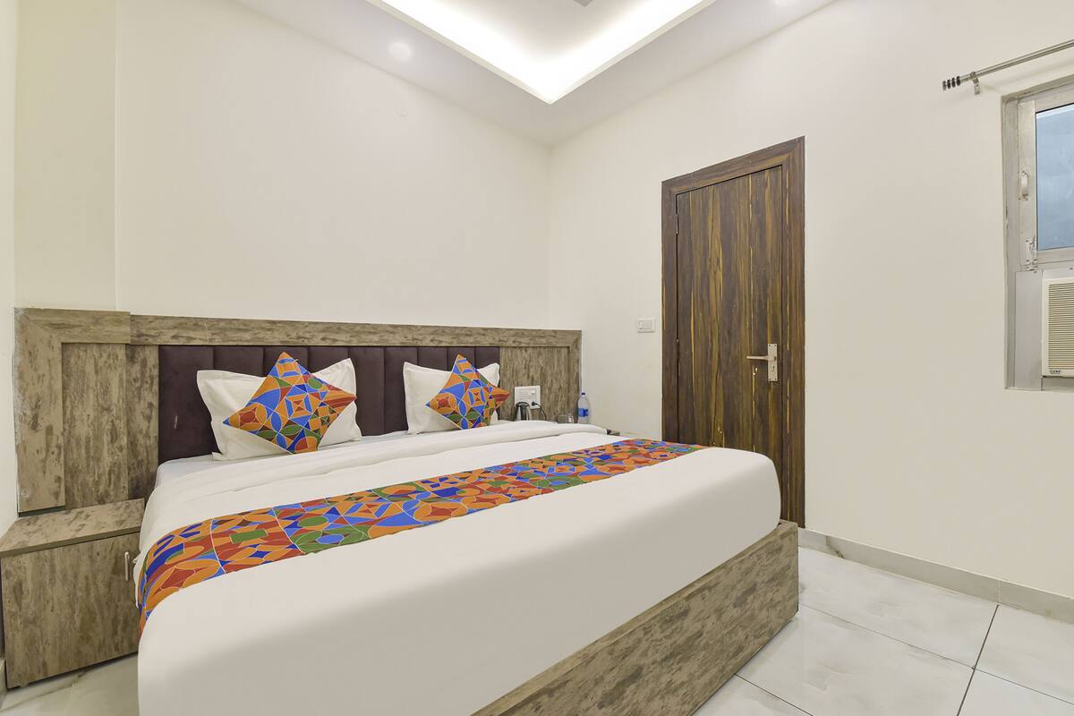 A bedroom with a bed, a wooden headboard, a window, and a door.