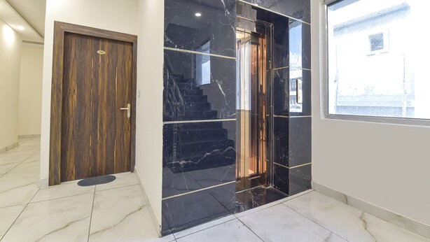 A hallway with a wooden door, a black marble wall, and a window. - Fabhotel Dev Palace (Haridwar)
