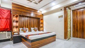 Un dormitorio con cabecera de madera, cama con almohadas coloridas, mesita de noche y cortina roja.