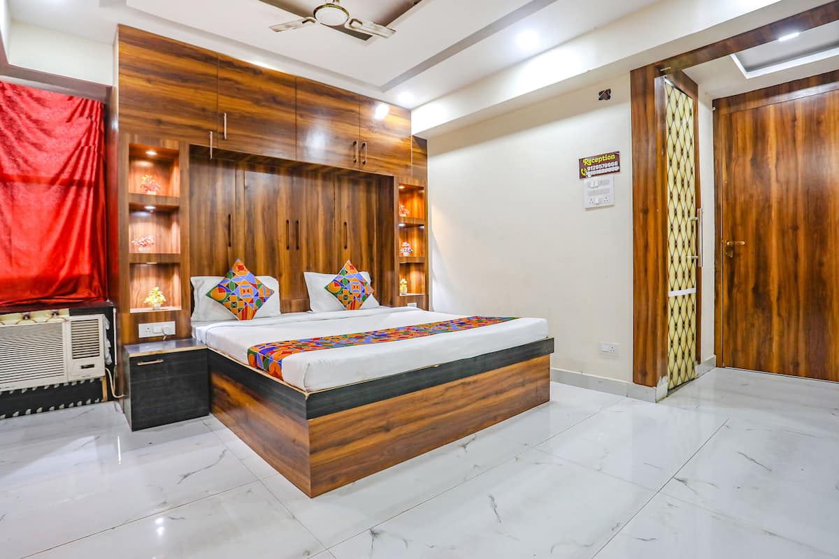 A bedroom with a wooden headboard, a bed with colorful pillows, a nightstand, and a red curtain.
