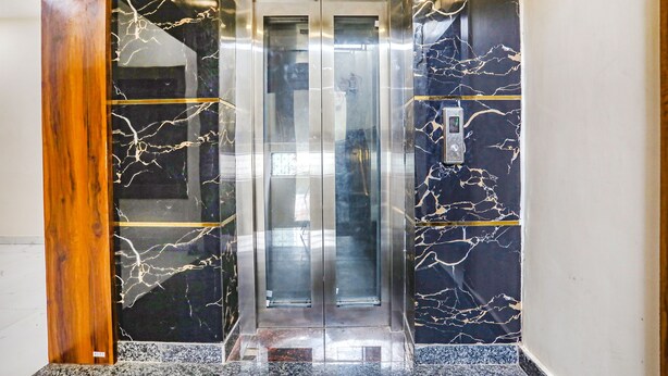 Un ascensor con una pared de mármol y un panel de madera a la izquierda.