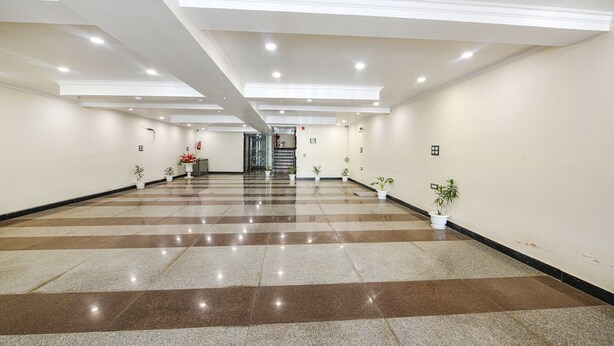 A spacious hallway with a checkered floor pattern, potted plants, and recessed lighting. - Fabhotel Prime Apple Tree Residency (New Delhi)