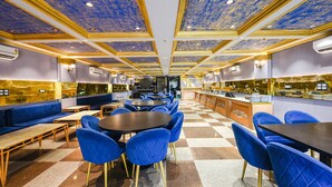 A restaurant with blue upholstered chairs and tables, a checkered floor, and a ceiling with a blue and gold pattern. - Fabhotel Prime Apple Tree Residency (New Delhi)