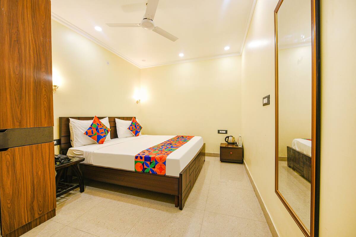 A hotel room with a bed, a nightstand, a mirror, and a ceiling fan.