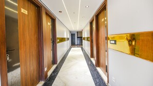 A hotel corridor with wooden doors, a marble floor, and recessed lighting. - Fabhotel Prime Apple Tree Residency (New Delhi)