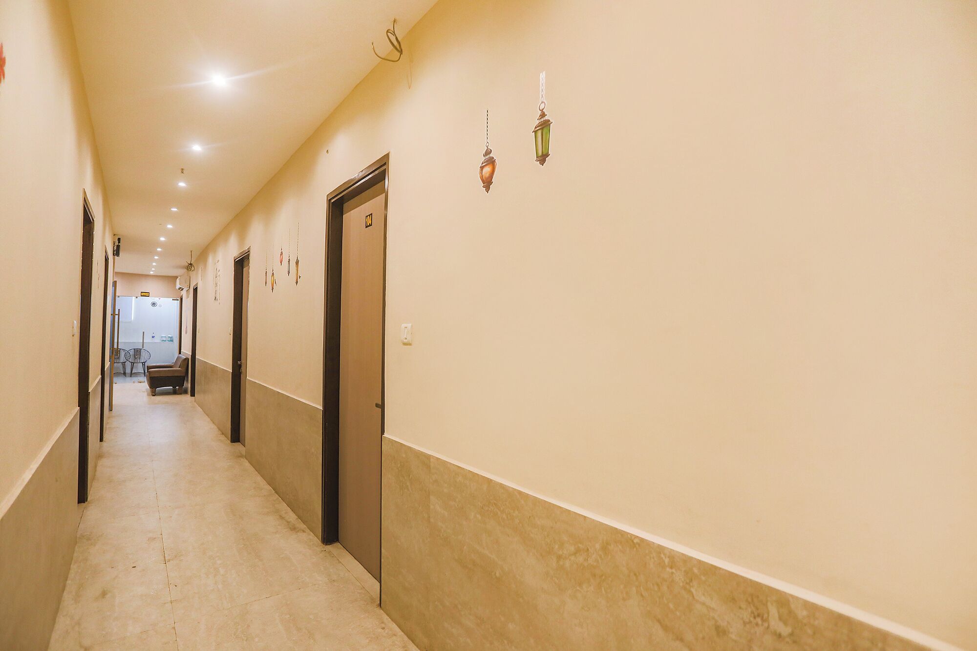A long, narrow hallway with doors on one side and a seating area with a table and chairs at the end.