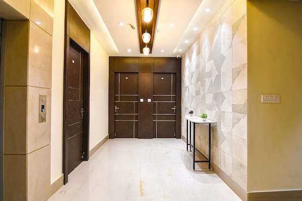 A hallway with a marble floor, a wall-mounted plant, and a geometric-patterned wall. - Fabhotel Samotel (Barasat)