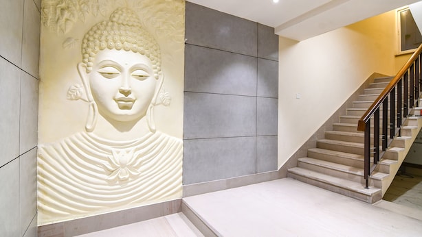 Un intérieur moderne agrémenté d’une grande fresque représentant Bouddha, d’un escalier et d’un design minimaliste.