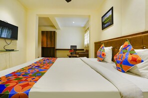 A hotel room with a large bed, a television mounted on the wall, and a view of the kitchen area. - Fabhotel Prime Hangout (Pune)