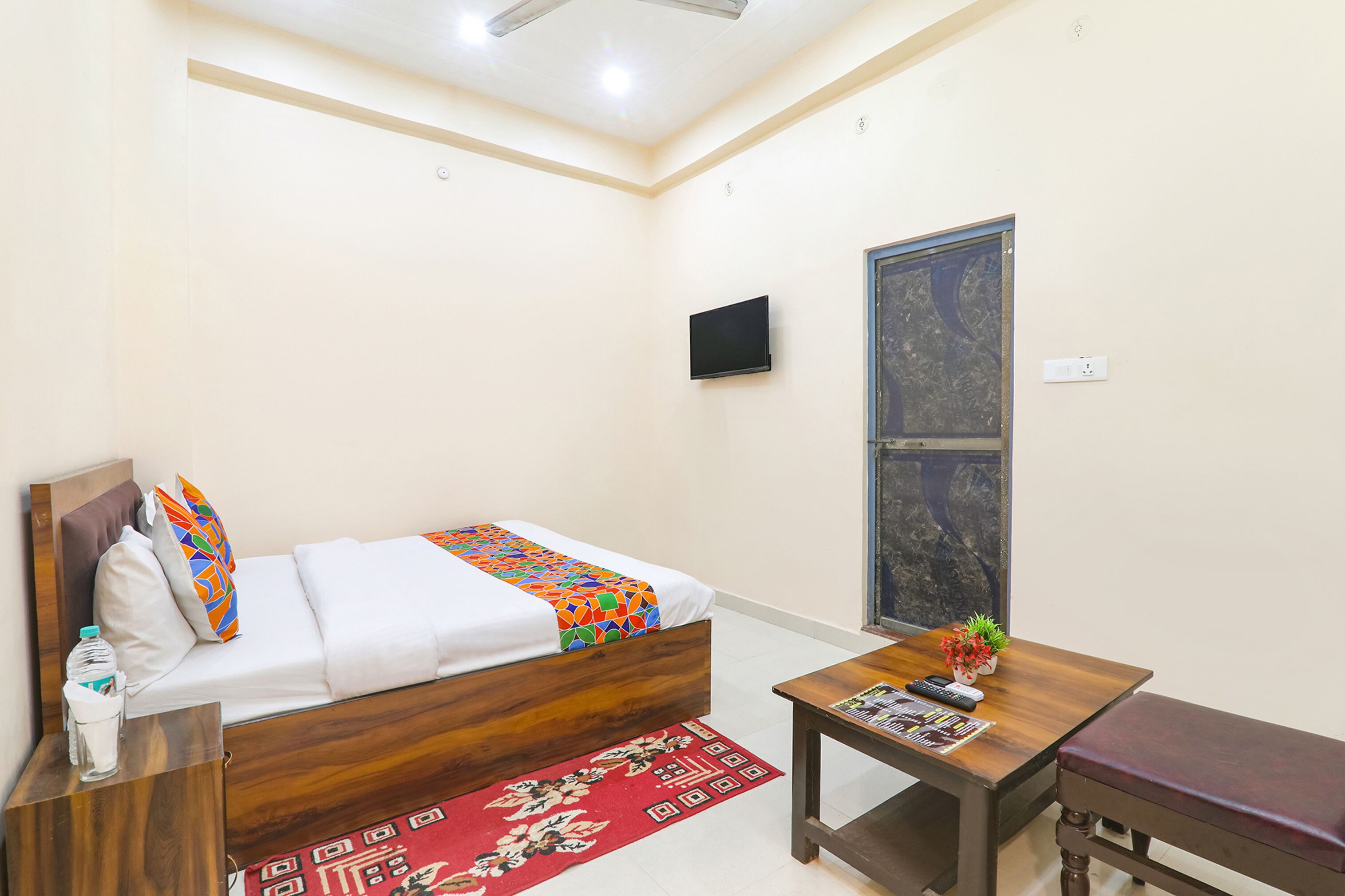 A hotel room with a bed, a wooden table, a small TV, and a window with a view.