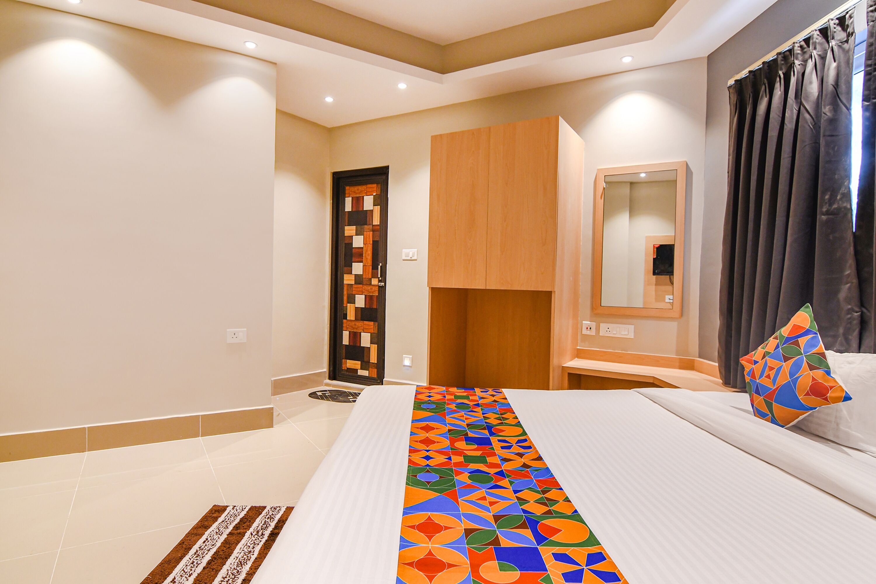 Una camera d'albergo con un letto grande, un armadio in legno, uno specchio e una finestra con tende.