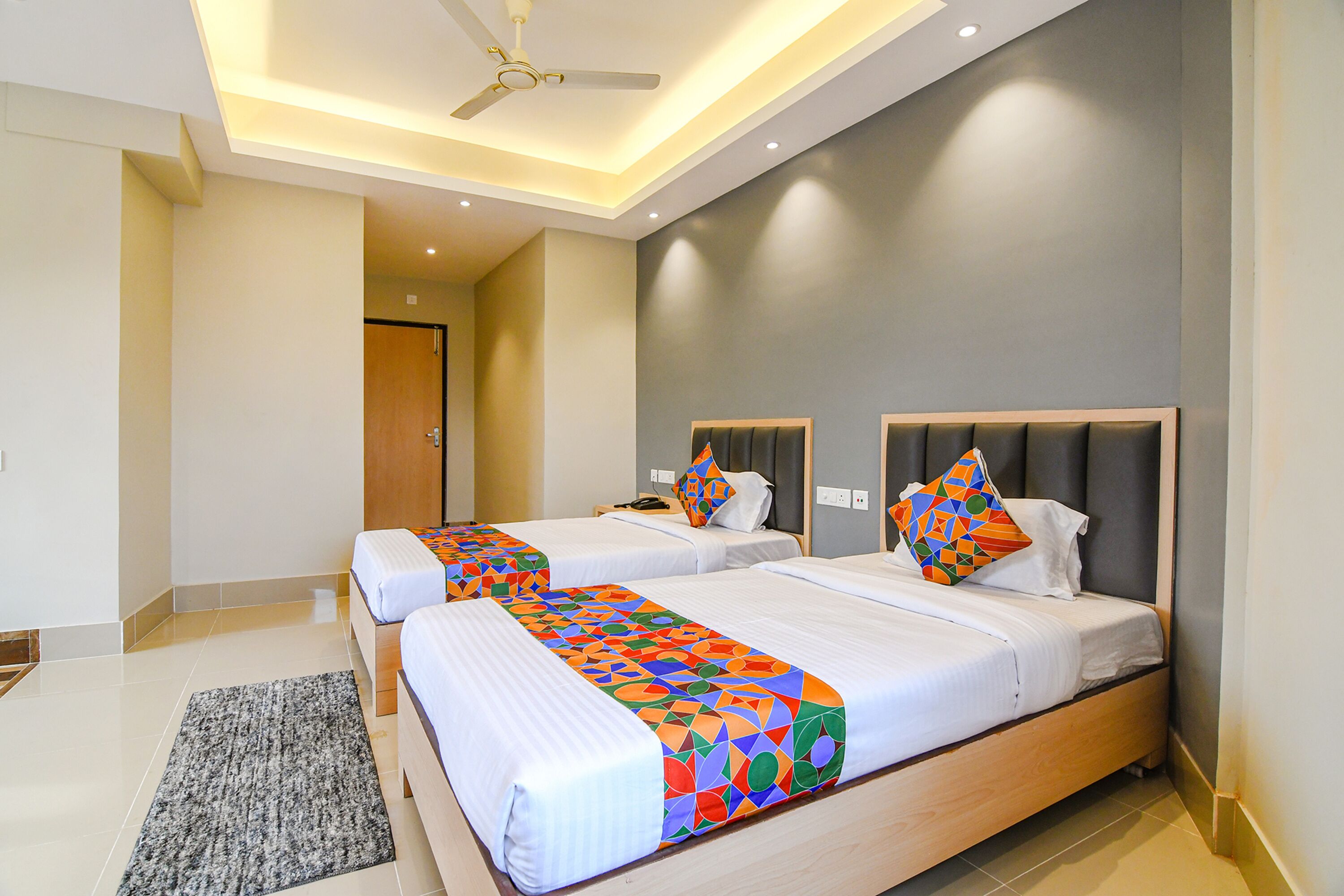 A hotel room with two beds, a ceiling fan, and a modern design.