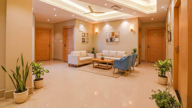 Uma sala de estar moderna com sofá, poltrona e mesa de centro, com ventiladores de teto e iluminação embutida.