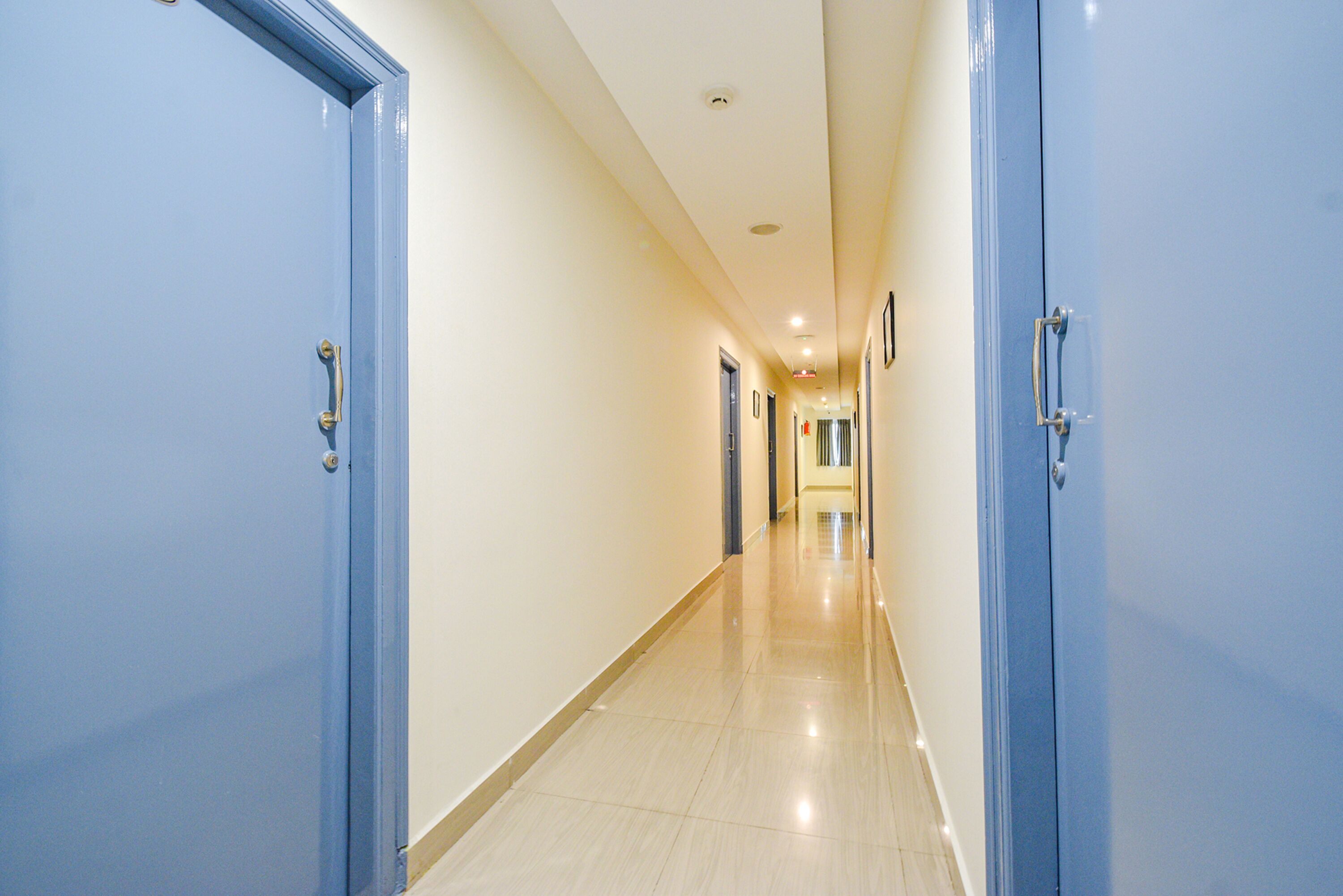 A long, narrow hallway with blue doors on both sides, leading to a series of rooms.