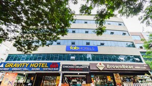 Een hotel met een bordje voor 'fabHOTELS' en aangrenzende bedrijven zoals 'Gravity Hotel Bar', 'Chicago Delights Pizza & Grill' en 'BrownBear Bakery'.