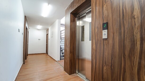 A hallway with wooden paneling and a modern elevator. - Fabhotel Chakra (Coimbatore)