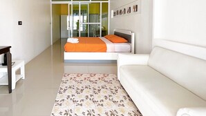 Een moderne hotelkamer met een groot bed, witte muren, een witte bank en een kamerkleed met dessin.