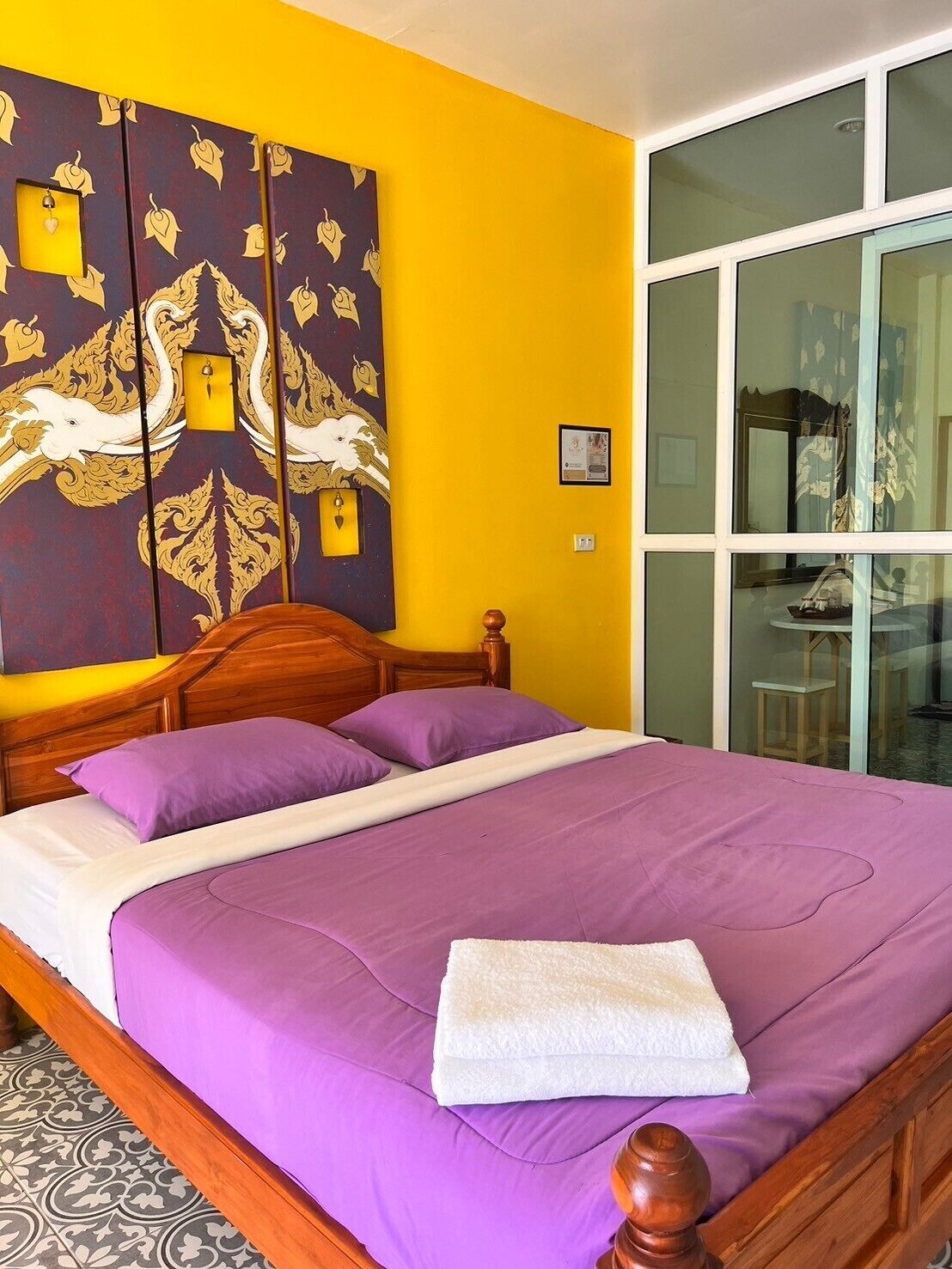 A room with a bed, a large decorative wall, and a sliding glass door.