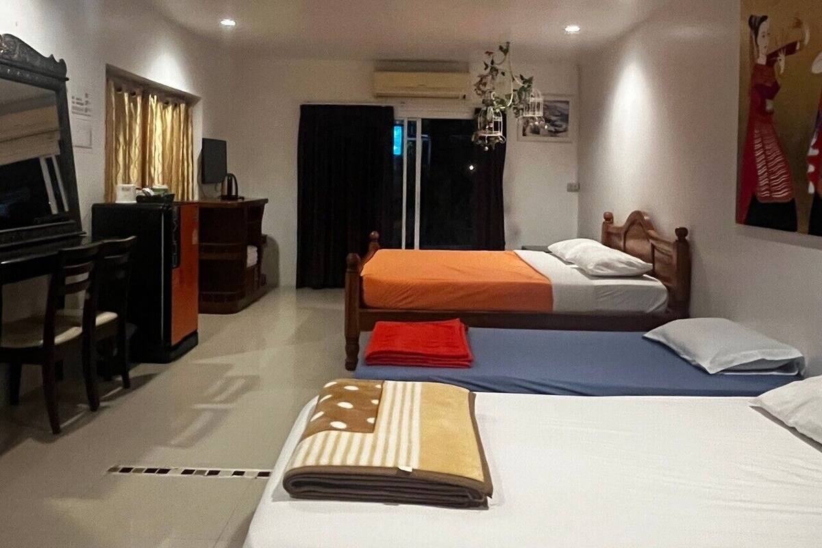 A hotel room with two beds, a desk, a chair, and a TV.