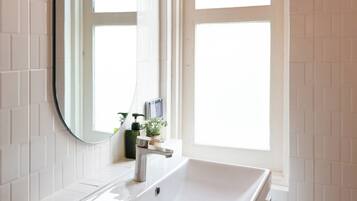 A bathroom with a white sink, a mirror, and a window with red curtains.