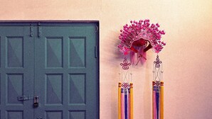A door with a padlock and a wall with Thai text and a hanging decoration.
