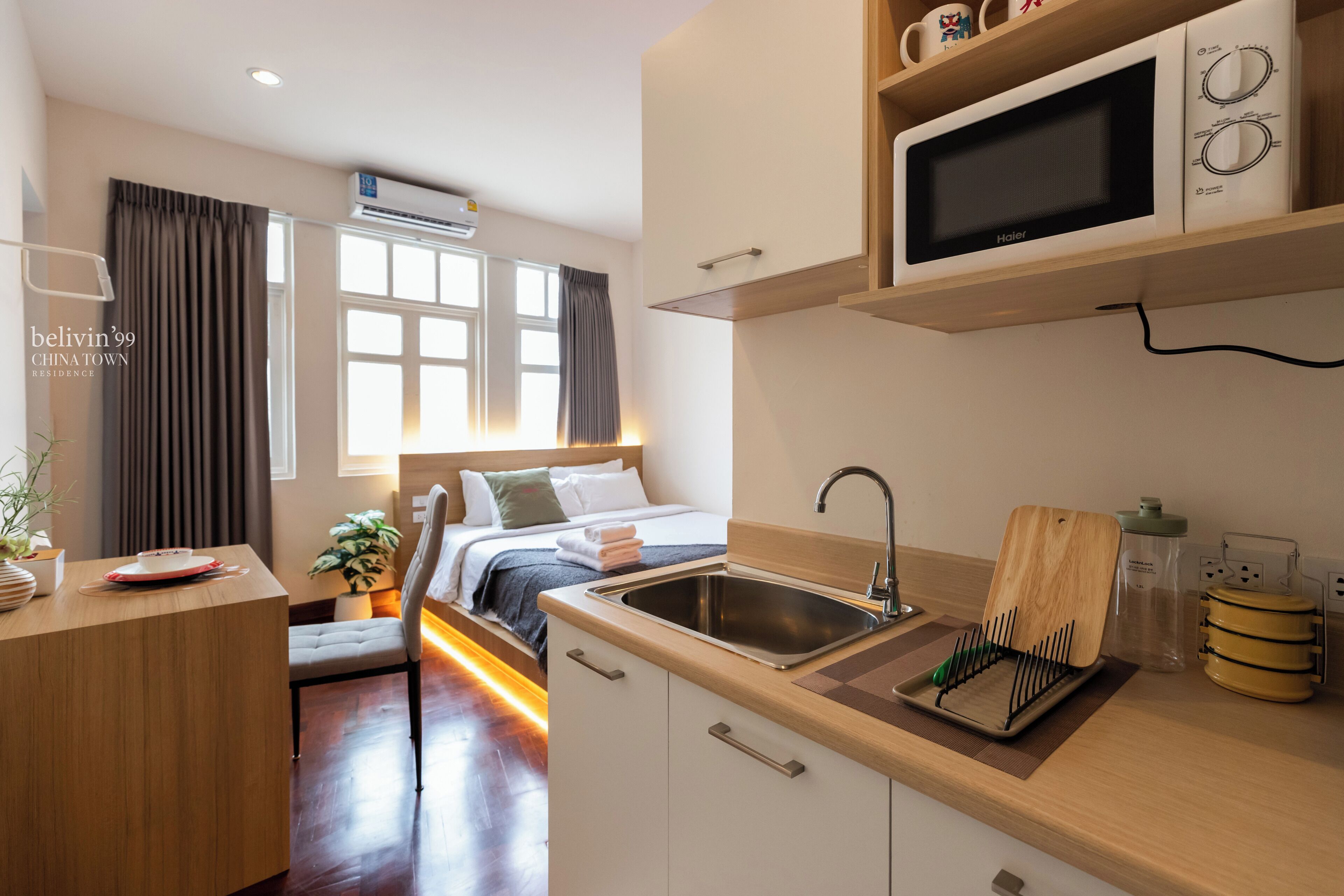 A compact hotel room with a kitchenette, a bed with a view, and a small dining area.
