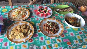 Een tafel met diverse gerechten en een geweven bamboestructure op de achtergrond.