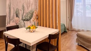 A dining area with a white table, black chairs, and a cactus-themed wall. - Elegant apartment in historic building in the heart of the Kalsa Palermo neighborhood. (Palermo)