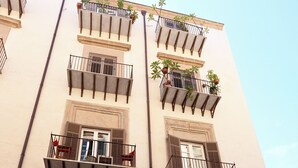A multi-story building with balconies, a large wooden door, and a parked car. - Elegant apartment in historic building in the heart of the Kalsa Palermo neighborhood. (Palermo)