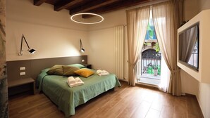 A bedroom with a bed, bedside lamps, a window with curtains, and a view of the outside. - Elegant apartment in historic building in the heart of the Kalsa Palermo neighborhood. (Palermo)