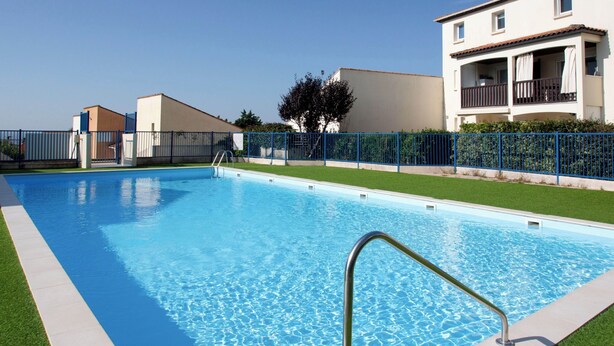 A rectangular swimming pool with clear blue water, surrounded by a metal fence and a grassy area. - Port Saint-Jacques by Interhome (La Bernerie-en Retz)