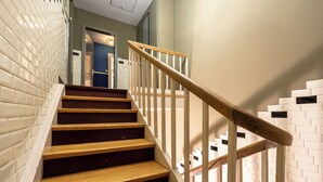 A staircase with wooden steps and white railings, leading to an interior space with a door and a wall with a herringbone pattern. - Zollhoes; Find the border! On discovery in the border area NL/DE (Haren (Ems))