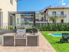 An outdoor kitchen with a grill, a sink, and a glass enclosure.