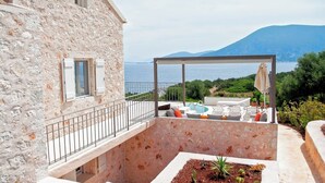 A stone building with a balcony overlooking a pool and a scenic view of the sea and mountains. - Casa di CLO sea front stone property,private pool, Fiscardo 500 m (Borgo Fiskardo)
