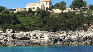 A coastal property with a large house on a rocky hillside, overlooking a clear blue sea. - Casa di CLO sea front stone property,private pool, Fiscardo 500 m (Borgo Fiskardo)