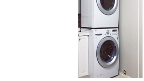 A stacked washer and dryer unit in a laundry room. - Cozy One Bed Suite Near Beach (White Rock)