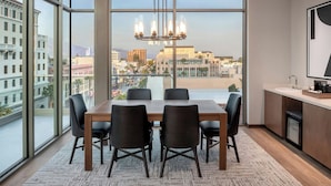 A modern dining area with a large table and chairs, a chandelier, and a city view through large windows. - AC Hotel Pasadena (Pasadena)