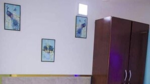 A hotel room with a bed, a wooden wardrobe, and two wall-mounted paintings. - HIGH STANDING APARTMENT CI (Abidjan)