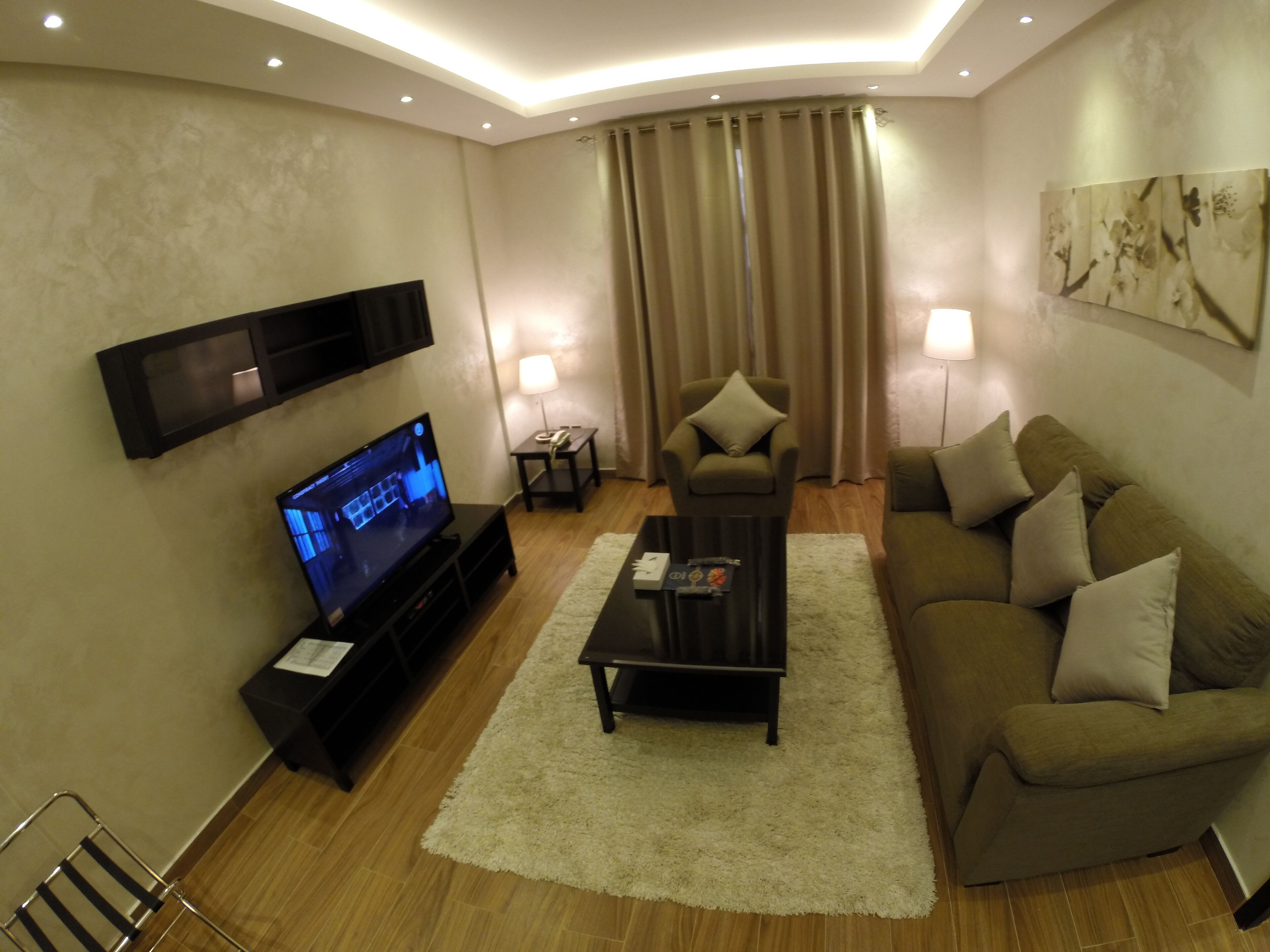 Uma sala de estar moderna com televisão de tela plana, um sofá, uma mesa de centro e uma poltrona.