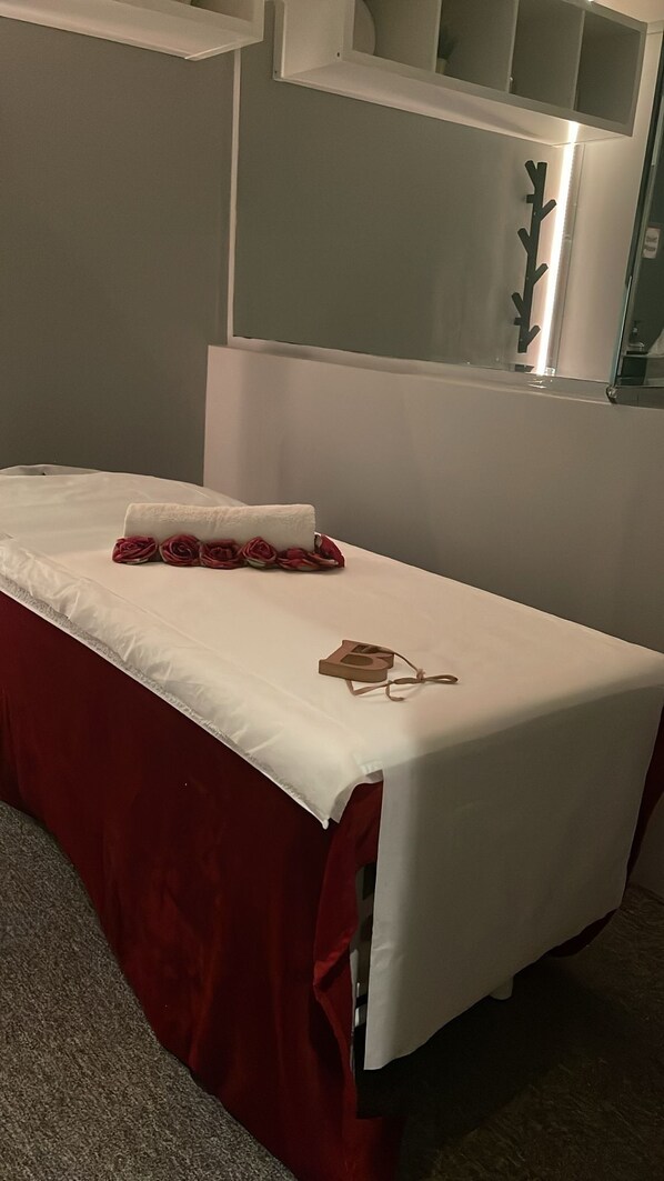 A neatly made bed with a white sheet and red accents, a small wooden object on the bed, and a mirror above it. - Le Park Hotel (Doha)