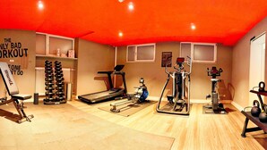 Un gimnasio en casa con una cinta de correr, una bicicleta estática y pesas diversas.
