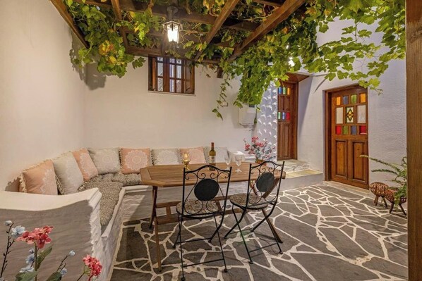 Una habitación acogedora con suelo de piedra, un banco de madera y una mesa con sillas.