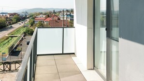 A balcony with a view of a residential area, a large window, and a ceiling fan.