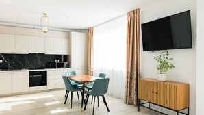 A modern kitchen with white cabinets, a black countertop, and a wooden dining table with blue chairs.