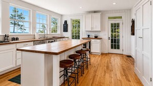 Una cocina amplia con una isla grande, taburetes de bar y armarios blancos.