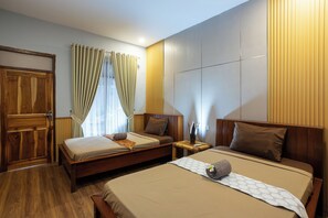 A hotel room with two beds, wooden flooring, a large window with curtains, and a wooden wardrobe. - Creative Trawangan Stay (Gili Trawangan)