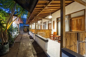 A covered outdoor area with wooden benches and tables, potted plants, and a tiled floor. - Creative Trawangan Stay (Gili Trawangan)