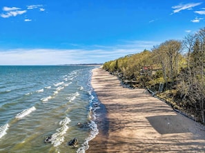 Eine Küstenstraße mit Strand auf der einen und Bäumen auf der anderen Seite.